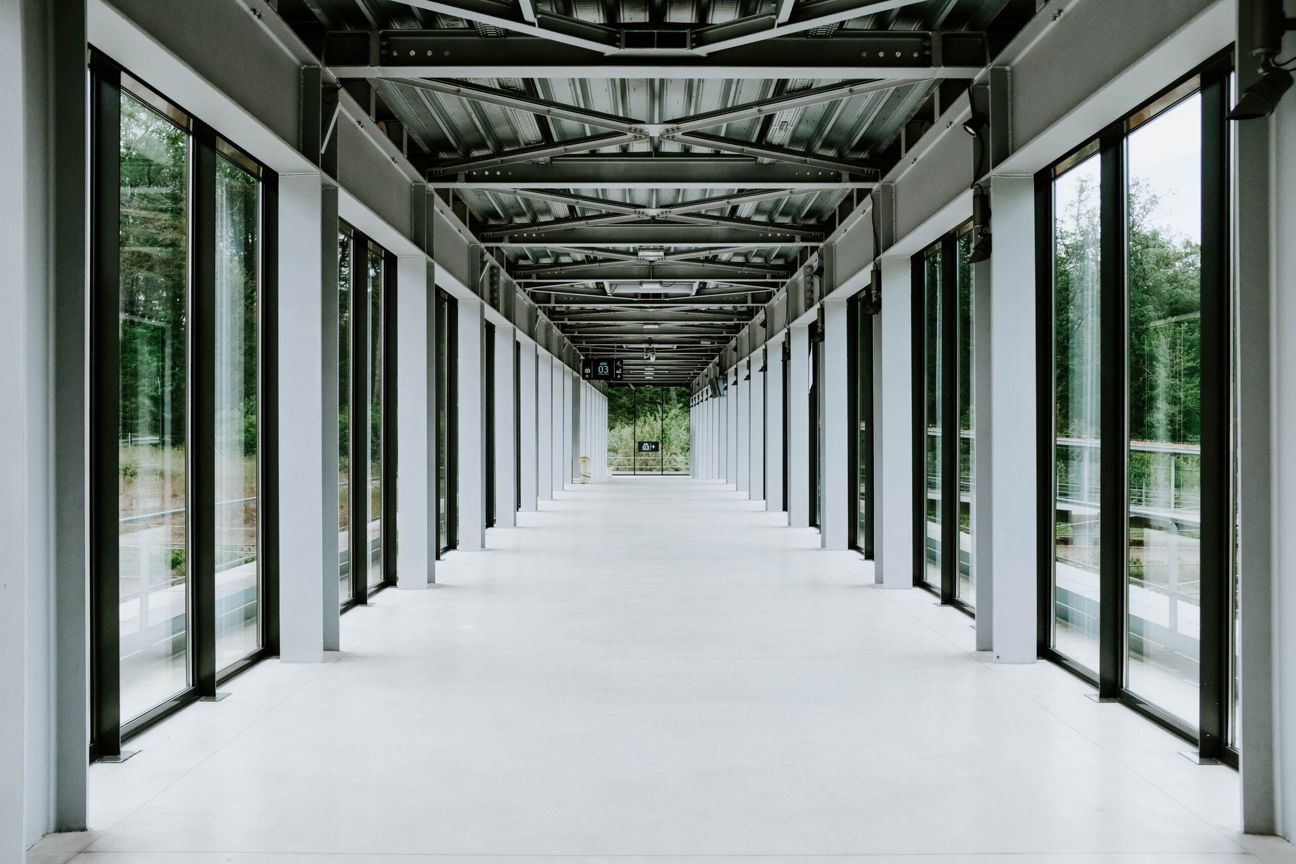 The white hallway with glass doors and metal ceiling in a modern building